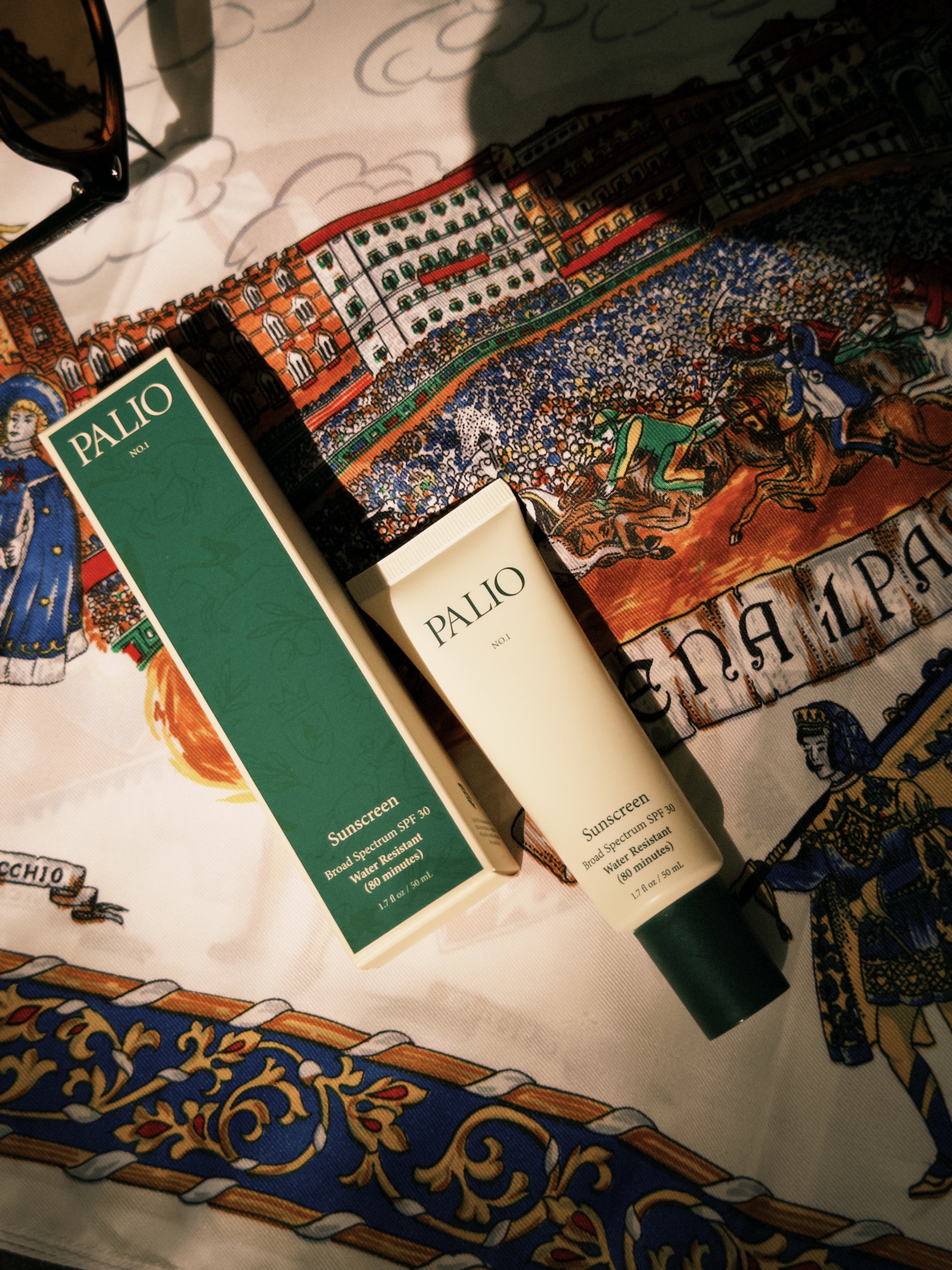 Palio sunscreen tube and box on a decorative fabric background