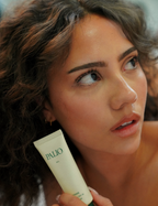 Woman holding a tube of Palio sunscreen with a blurred background